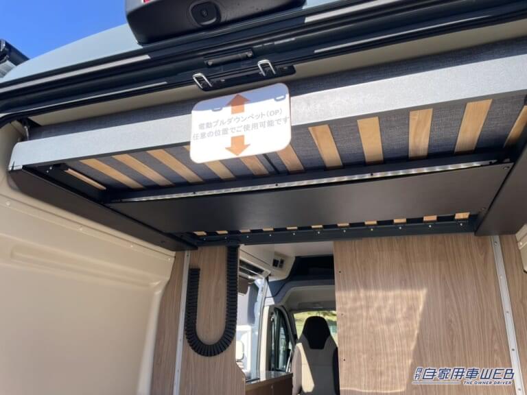 ベッドは電動で昇降する仕組み。使用しないときは天井に張り付くようになるので、車内スペースを有効に活用できる。|「回転シート良いよね」快適すぎて、もはや家。家庭用エアコン・キッチン・電動ベッド付き。住みたくなるキャンピングカー。