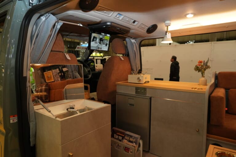 運転席後方に冷蔵庫、大型収納庫。助手席後方に鏡付きシンクを配置。11.6インチのフリップダウンモニターも標準装備する。