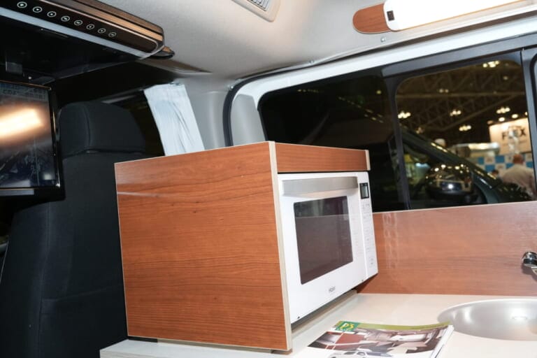 電子レンジも標準装備。白モノ家電はインテリアと同系の家具で覆い車内の雰囲気に調和させている。