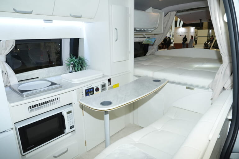 車内は白を基調としたデザインで高級感があふれる。これが走るハイクラスワンルームの全容だ。｜もはや「自走する家」トヨタ車が「高級ワンルーム」になるなんて。IHコンロ・電子レンジ・冷蔵庫・エアコンまで完備。