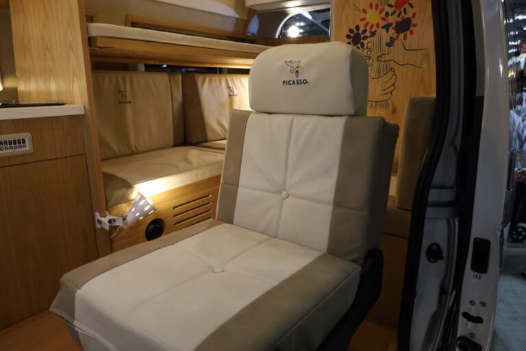 運転席、助手席と2列目シートを合わせて3名の前向き乗車が可能。2列目シートは走行時とリビング＆ベッド展開時に応じてトランスフォーメーションできる。シートや家具類もピカソ作品のレプリカが室内に彩りを添える。｜快適トヨタ車「本当に車内なのか…？」もはや家、極上室内は家族で暮らすように旅できる。キッチン・ベッド・エアコン…何でも揃ってる！