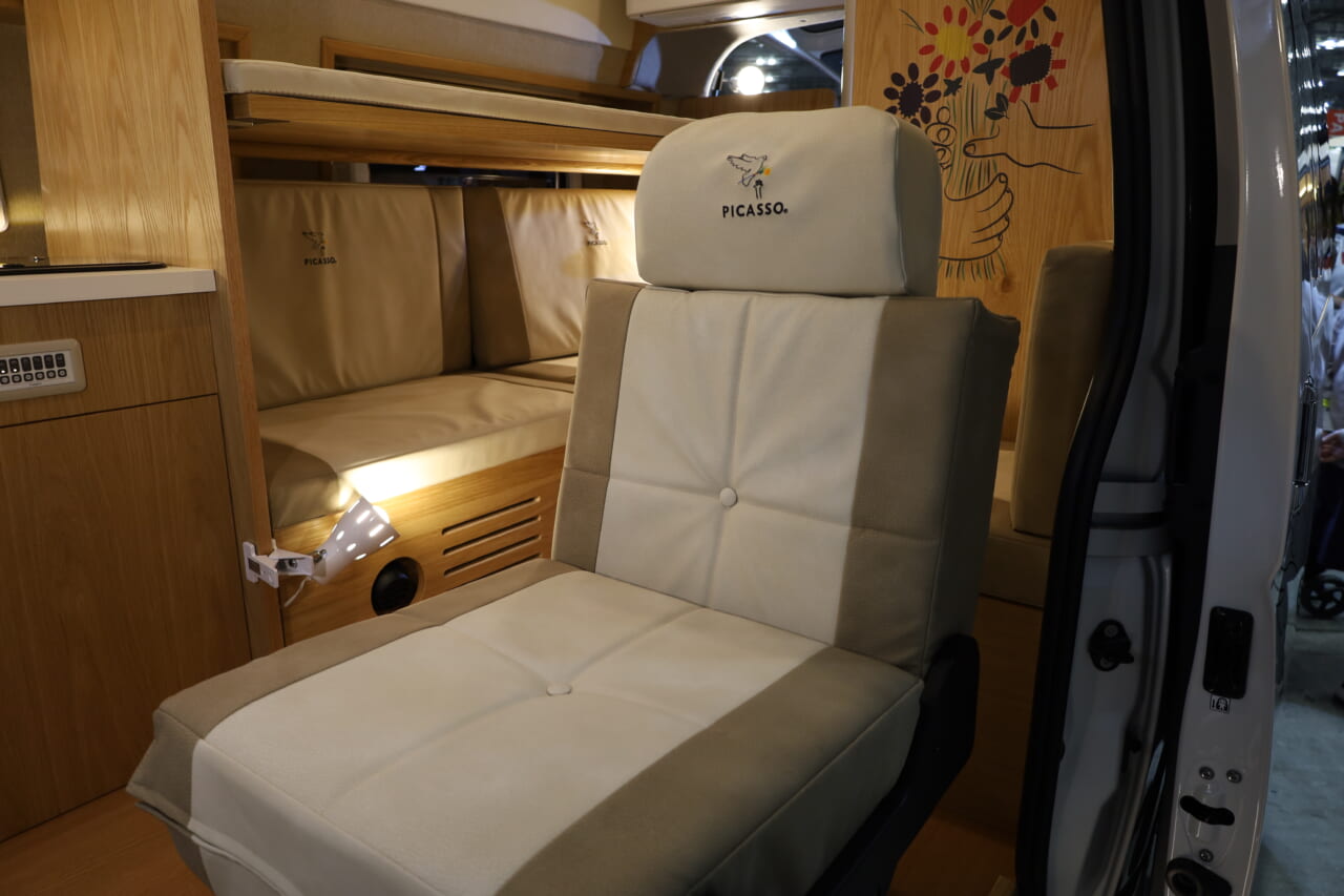 運転席、助手席と2列目シートを合わせて3名の前向き乗車が可能。2列目シートは走行時とリビング＆ベッド展開時に応じてトランスフォーメーションできる。シートや家具類もピカソ作品のレプリカが室内に彩りを添える。｜快適トヨタ車「本当に車内なのか…？」もはや家、極上室内は家族で暮らすように旅できる。キッチン・ベッド・エアコン…何でも揃ってる！