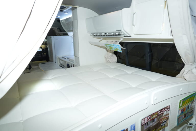 ベッドサイズは180×140cmで大人2人がゆったりと横になれる。｜もはや「自走する家」トヨタ車が「高級ワンルーム」になるなんて。IHコンロ・電子レンジ・冷蔵庫・エアコンまで完備。