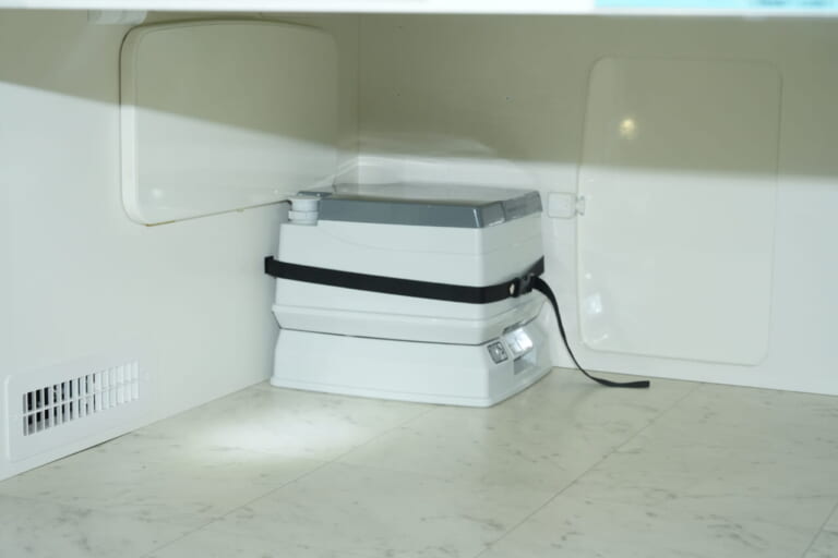 未使用時は荷室に収納。使用時は簡易トイレを車内前方に運び、カーテンで仕切れば簡易トイレルームになる。｜もはや「自走する家」トヨタ車が「高級ワンルーム」になるなんて。IHコンロ・電子レンジ・冷蔵庫・エアコンまで完備。