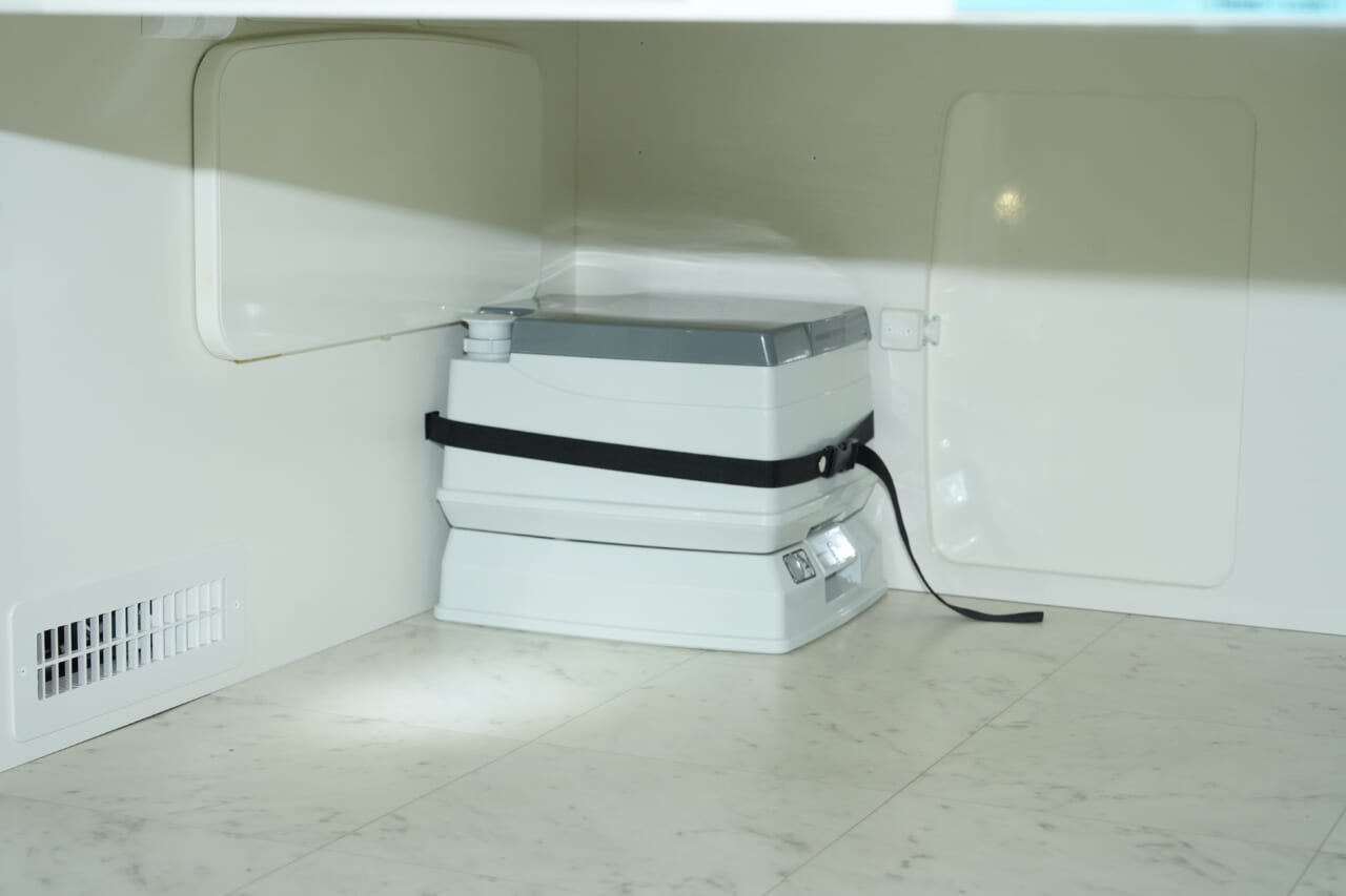 未使用時は荷室に収納。使用時は簡易トイレを車内前方に運び、カーテンで仕切れば簡易トイレルームになる。｜もはや「自走する家」トヨタ車が「高級ワンルーム」になるなんて。IHコンロ・電子レンジ・冷蔵庫・エアコンまで完備。
