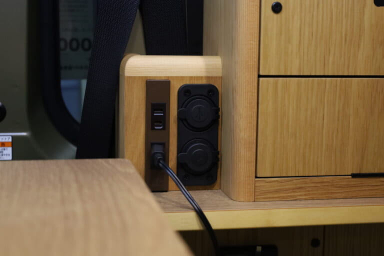 100VコンセントとUSBポートは12Vクーラーがある棚の下部に設置。就寝時も利用しやすい。｜「軽なのに…“最強”!?」無骨カッコいい、安っぽくない！軽キャンパーに見えない存在感。