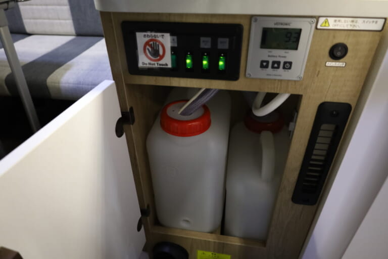 シンク下に装備する給排水タンクの容量は13L。エントランス脇なのでタンクの積み下ろしも楽に行える。｜「本当に660ccか？」「ちょっとコレは凄すぎる…」マジで快適すぎるぞ、車内が家みたい。圧倒的な存在感と満足の室内空間が素敵なキャンピングカー。