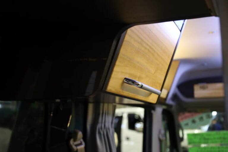 上部左右にキャビネットと収納スペースを装備。1～2名のクルマ旅なら十分な収納力だ。｜「えぇーっ 流石にスゴイ」「本当に軽自動車ですか？」バンライファーにぶっ刺さる！まさかの天然木が胸を打つ、あれもこれも詰まった軽キャンパー。