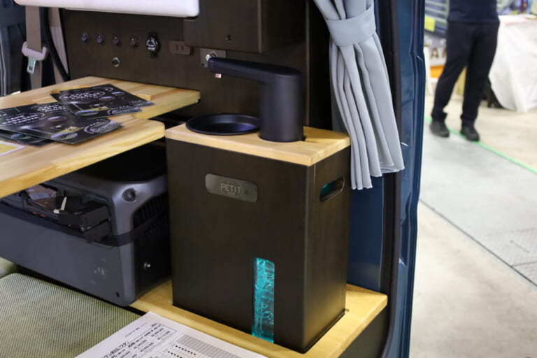 2Lペットボトルの給•排水タンクを搭載する小型ギャレー。本体ごと車外に持ち出して使うこともできる。｜「えぇーっ 流石にスゴイ」「本当に軽自動車ですか？」バンライファーにぶっ刺さる！まさかの天然木が胸を打つ、あれもこれも詰まった軽キャンパー。
