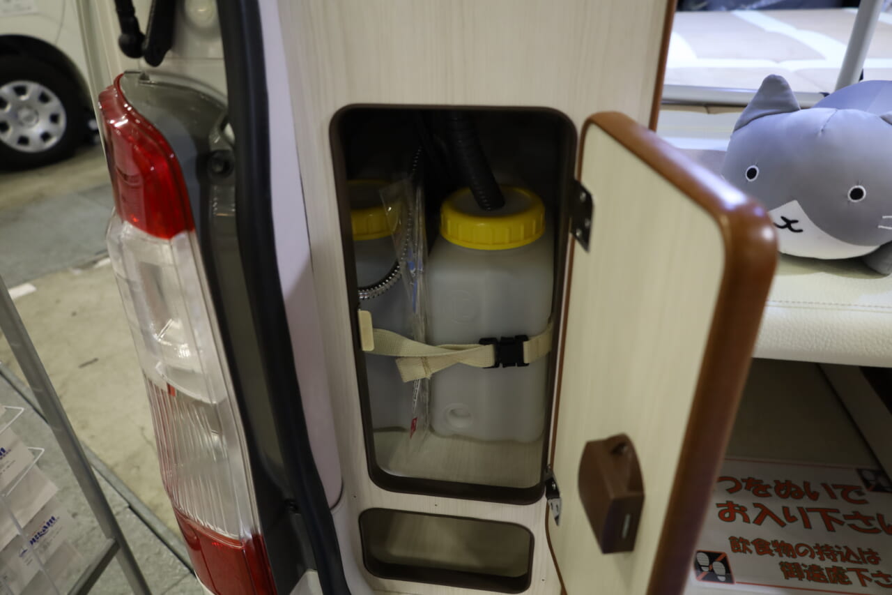 給•排水タンクの下にも収納庫があり、ダスターやブラシなど水回りの小物収納などアイデア次第で使い道が広がりそうだ。|「えぇーっ もはや家だぞ…」普通のトヨタ車と思いきや…暮らせるレベルの車内に驚いた。キッチン・冷蔵庫・クーラー・電源にベッドまで!
