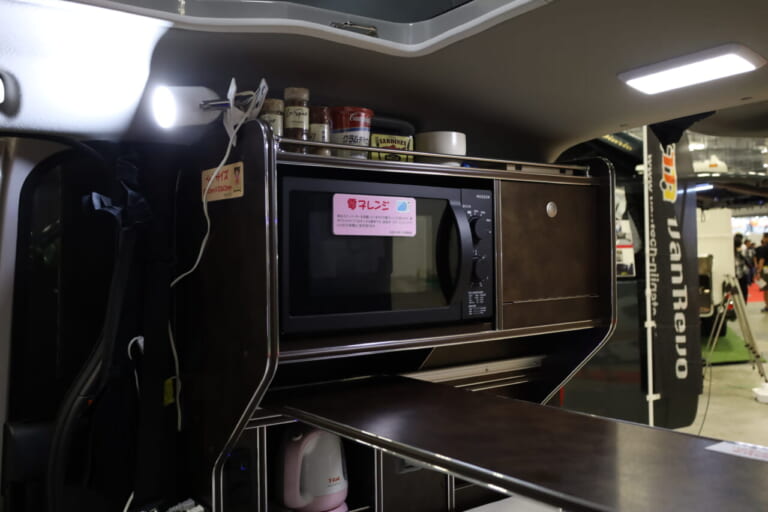 ビルトインされた電子レンジは18Lのフラットタイプで庫内のお手入れも楽。上部には調味料などを置くのにちょうど良い収納スペースがある。｜トヨタの“超すごい”ミニバンが「もはや部屋」みたいな車内に。好きな人にブッ刺さる、充実装備の特別仕様車は「理想的」すぎてグッと来る。