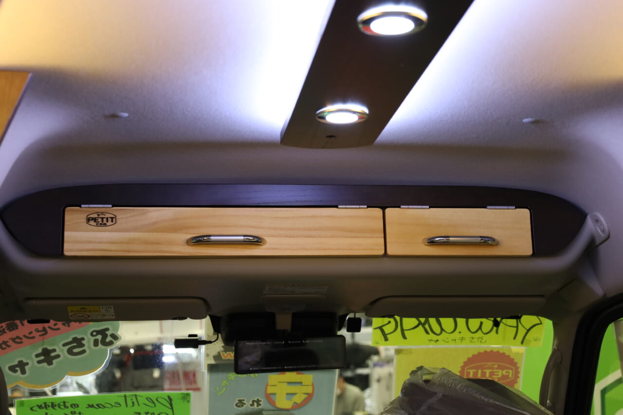キャリイの運転席•助手席上にあるオーバーヘッドシェルフにも天然木の扉を設置。車内全体のインテリを統一し、細部までおしゃれなキャンパーに仕上げられている。｜「えぇーっ 流石にスゴイ」「本当に軽自動車ですか？」バンライファーにぶっ刺さる！まさかの天然木が胸を打つ、あれもこれも詰まった軽キャンパー。
