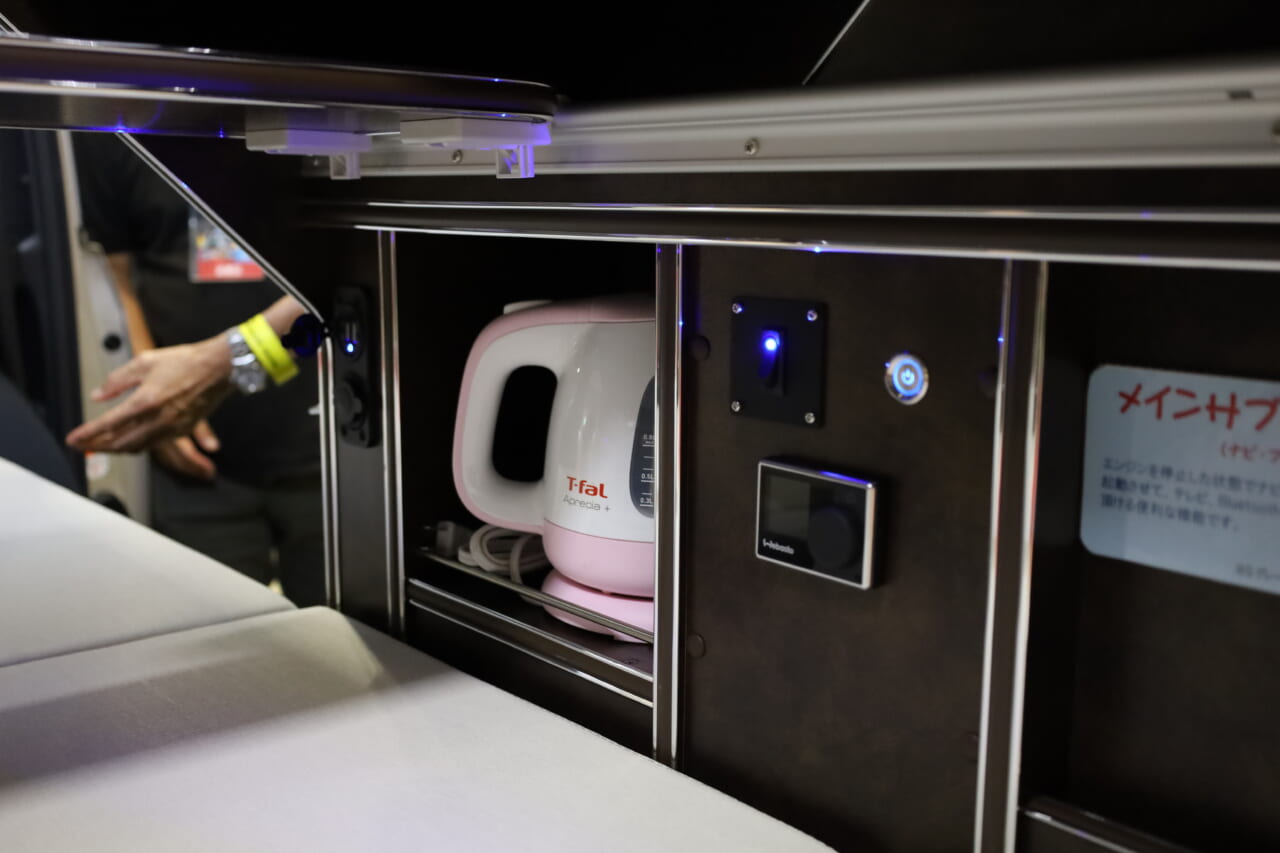 電子レンジ下の収納は電気ケトル専用庫。キャビネット側面にはAC100Vコンセントとインバータースイッチが配置され、家電が手軽に使える。｜トヨタの“超すごい”ミニバンが「もはや部屋」みたいな車内に。好きな人にブッ刺さる、充実装備の特別仕様車は「理想的」すぎてグッと来る。