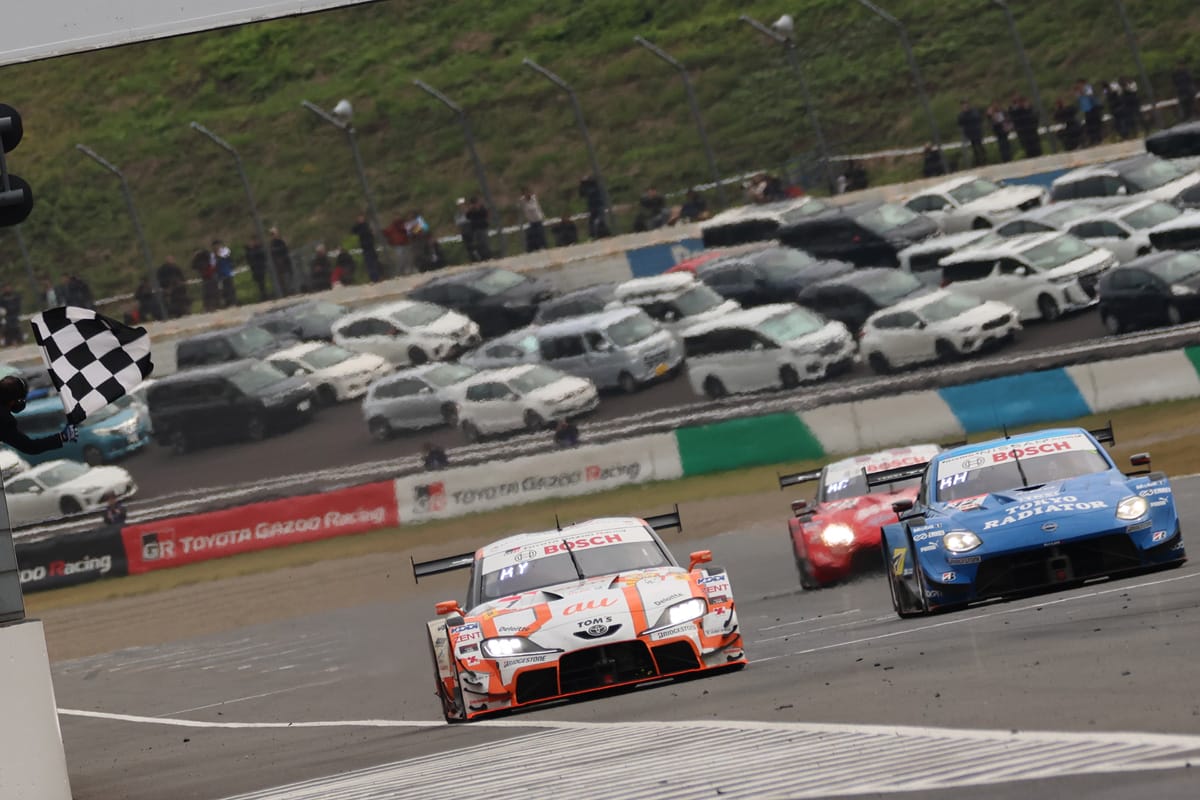 チェッカーを受けるトップ2台｜SUPER GT 最終戦でau TOM’S GR Supraが優勝でチャンプ決定！坪井選手は前人未到の3連覇達成!!
