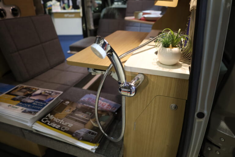 シンクにはカップホルダーも装備。給水タンクはシンク下のキャビネット内に配置。シャワーヘッドは伸縮式で、リヤゲート側にはホルダーもあり外でも使用できる。|「軽とは思えない」チープさ排除でブッ刺さる、まるで走るタイニーハウス。普通に手の届く価格帯が嬉しい軽キャンパー。