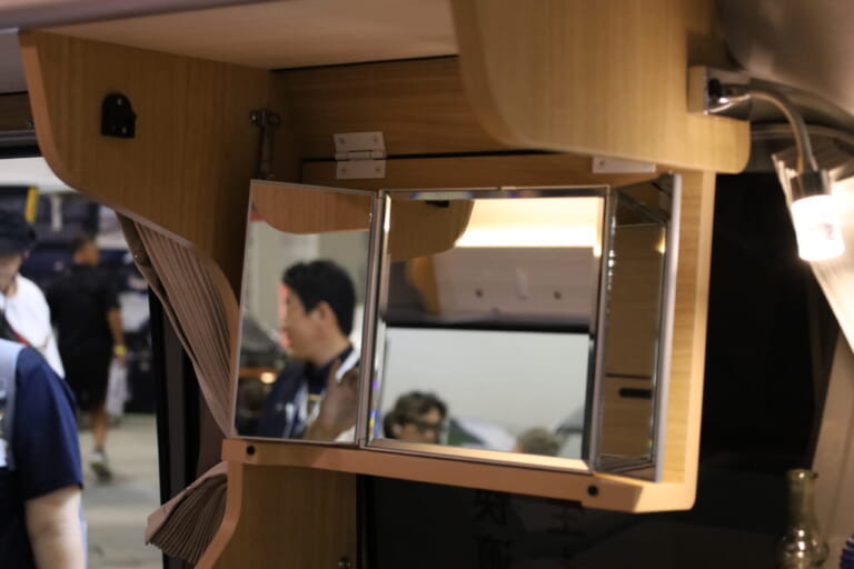 展示車はシンクの上部にオプションの三面鏡を装備。フリップダウン式で走行時は収納すればガタつくこともない。|「軽とは思えない」チープさ排除でブッ刺さる、まるで走るタイニーハウス。普通に手の届く価格帯が嬉しい軽キャンパー。