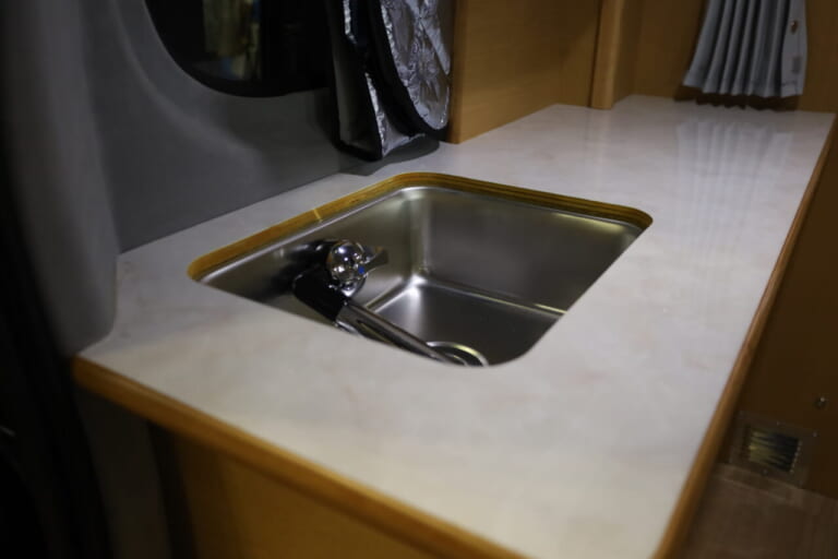  収納式の蛇口を装備するシンク。フタをすれば広い作業台になる。｜「おいおい、これは住めちゃうぞ」クルマの中に電子レンジや冷蔵庫、キッチンまで装備。もはや1Kの部屋みたいで便利に使えそう。