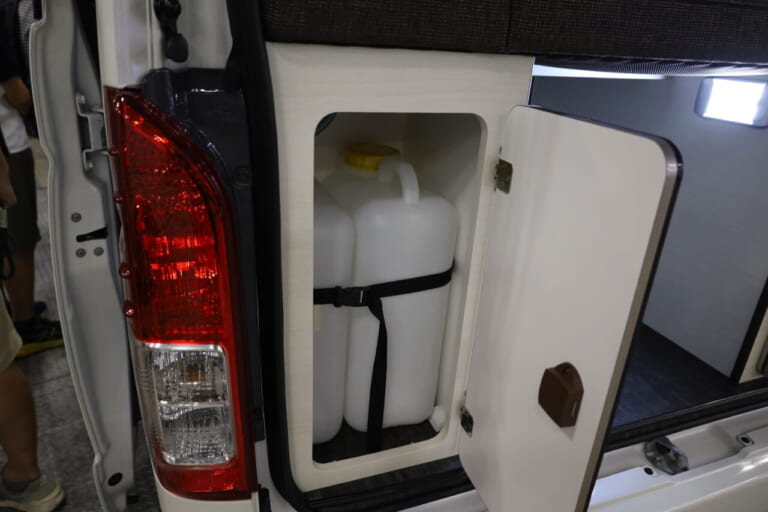 給水タンクはリヤゲートを開けてすぐの最後部の収納庫に内蔵。ここも生活感を隠しつつ、給水が手軽に行える。|トヨタ車「衝撃の広さに感服」サイズ選びの新基準、ありそうでなかった珠玉の一台。経済的にクルマ旅。駐車場にも困らない。