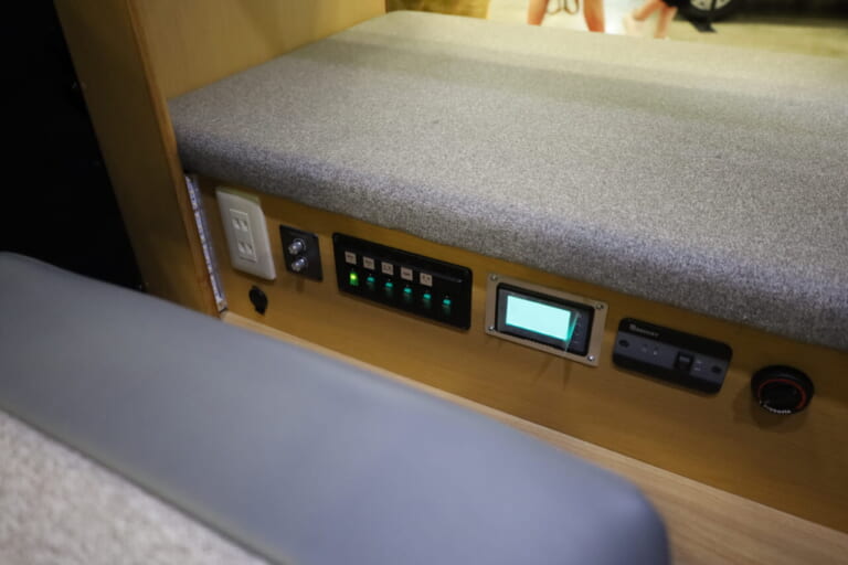 下段ベッド下にコンセント類や集中コントロールスイッチなどを配置。ダイネットからも寝ていても操作しやすい。｜「おいおい、これは住めちゃうぞ」クルマの中に電子レンジや冷蔵庫、キッチンまで装備。もはや1Kの部屋みたいで便利に使えそう。