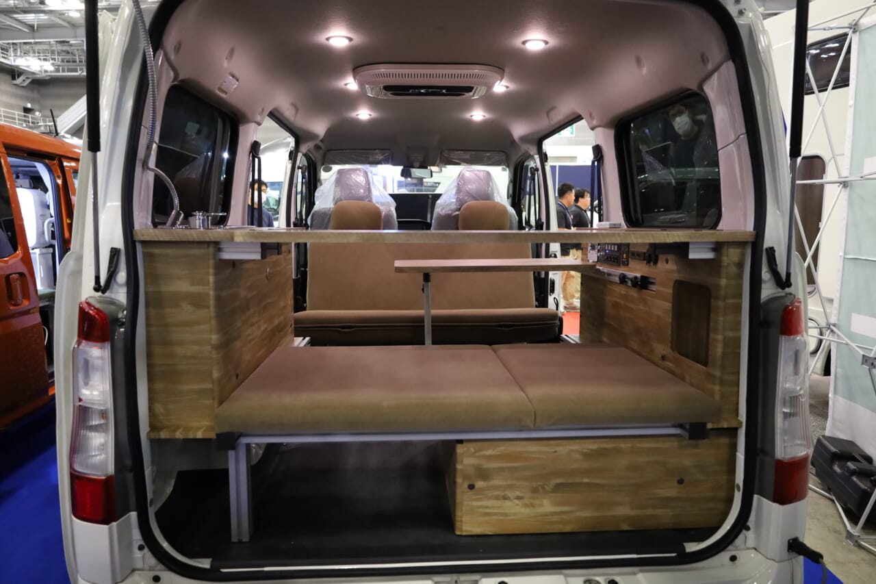 対面ダイネットモードの室内。天井にはLED照明が設置され、車中泊の夜もシーンに合わせて快適にすごせる。就寝時はセカンドシートとリヤ側のベンチを連結することで全長約1800mm×幅約1200mmのフルフラットベッドになり、大人2人でもゆったり眠れる。|はっきり言って「ここに住めます」トヨタ車の室内は「まさにワンルーム」絶妙なサイズ感がグッドだね。キッチン・シャワー付き。