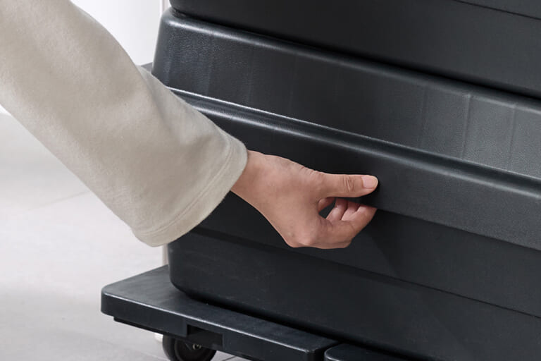 再生ポリプロピレン入り 頑丈収納ボックス 浅型 ダークグレーに手をかけている写真|「やっぱいいね」「無印良品だとこうなるんだ?」クルマに積むのにちょうどいい。MUJI人気定番アイテムに再生材使用の新ラインナップ登場