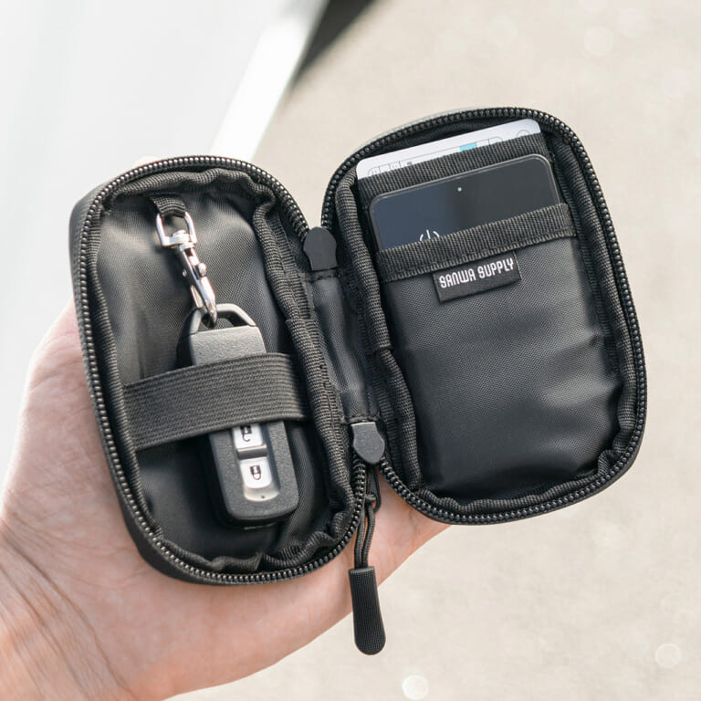 サンワサプライ スマートキーケース（200-CAR105）のファスナーを開いて、手に持っている｜「コレ,工夫がスゴい…」防水素材&止水ファスナーで中身も安心。クルマに乗る人にオススメ。ちょうどいい収納力のスマートキーケースを紹介