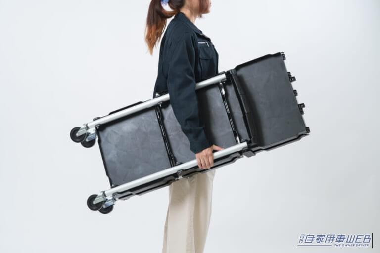 折りたたんだ状態のクラフトワークス クラフトワゴン（ファンスタンダード）を女性が抱えている画像｜「この発想はなかった…」とんでもない格納性！クルマの空いたスペースにもスッポリ積載。一度使うと手放せない、超便利アイテムを紹介！［クラフトワゴン］