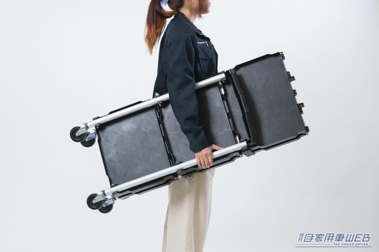 折りたたんだ状態のクラフトワークス クラフトワゴン（ファンスタンダード）を女性が抱えている画像｜「この発想はなかった…」とんでもない格納性！クルマの空いたスペースにもスッポリ積載。一度使うと手放せない、超便利アイテムを紹介！［クラフトワゴン］