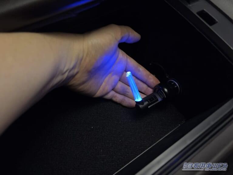 210系トヨタ クラウンのコンソールボックス内のアクセサリーソケットに、カーメイトのクリスタルランプ USBタイプ ブルーLED（CZ406）をを装着し点灯。手を添えた画像｜「使わないなんてもったいない…」見落としがちな車内装備活用術。「コレめっちゃいいわ…」カー用品で見つけたグッズを購入。実際にクルマに装着！