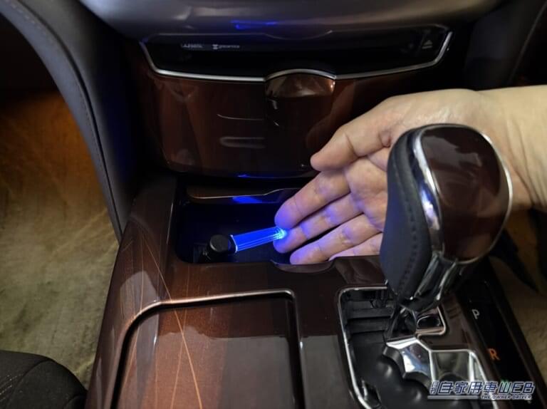 カーメイトのクリスタルランプ USBタイプ ブルーLED（CZ406）を、210系クラウンの小物入れ内のUSBに装着して点灯させ、手を添えた画像｜「使わないなんてもったいない…」見落としがちな車内装備活用術。「コレめっちゃいいわ…」カー用品で見つけたグッズを購入。実際にクルマに装着！