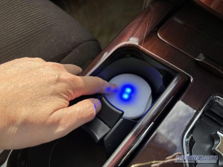 210系クラウンのカップホルダーにセットされた、カーメイトのブラング LEDコースター（FR1002）の電源を入れている画像｜「えっ…なにコレ？」 ドリンクホルダーに置くだけで愛車が劇変！「この発想はなかった…」効果抜群のアイデアカーグッズを紹介