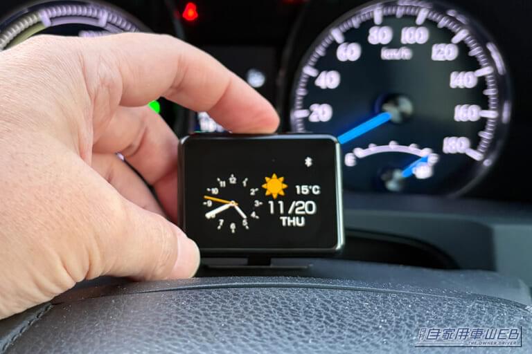 クルマのインパネ付近に設置されたカシムラのスマートクロック（AK-230）の本体上部にあるボタンを操作する画像｜「結果、大正解でした」小型モニターを車内に設置。ドライブ中に情報を表示。あらゆる車種に対応するガジェットを購入！ 実際に使用した印象をレポート