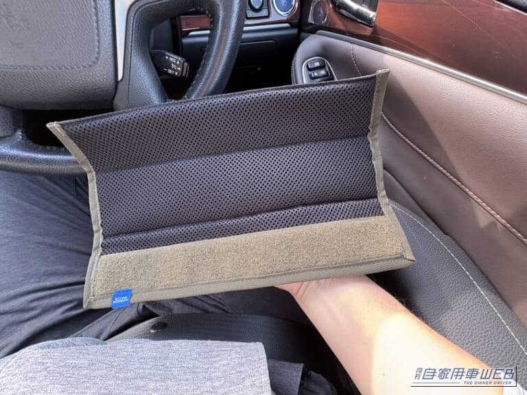 210系クラウンの運転席で、開いた状態のゴードンミラーのコーデュラ シートベルトパッド（OLIVE DRABカラー）を手に持っている写真｜「シートベルトって洗えないよね…」夏場は汗でニオイも気になる。だったらコレ使ってみて！ デザイン性が高く通気性も抜群「ゴードンミラー・コーデュラ シートベルトパッド」