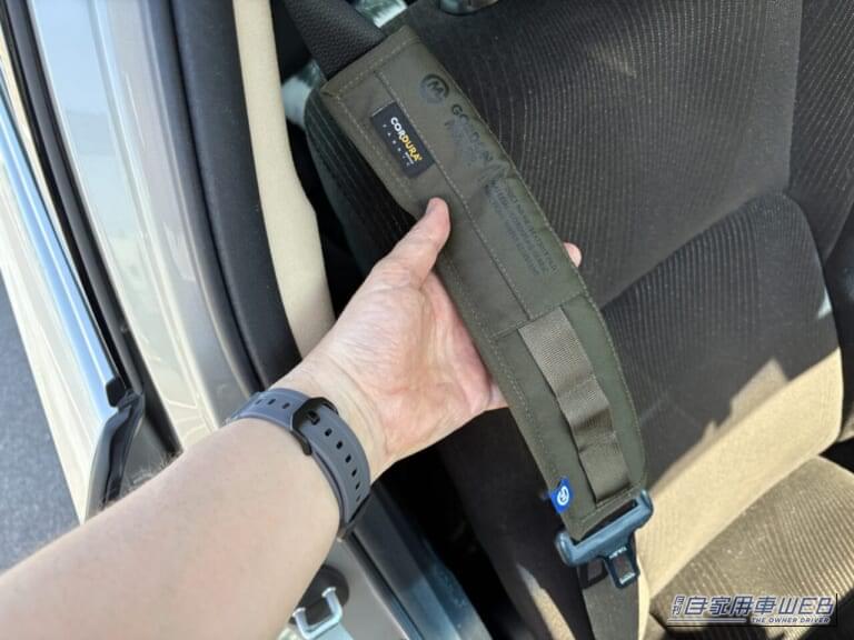 210系 トヨタクラウンのシートベルトに装着した、ゴードンミラー コーデュラシートベルトパッド（OLIVE DRABカラー）を手で持っている写真｜「シートベルトって洗えないよね…」夏場は汗でニオイも気になる。だったらコレ使ってみて！ デザイン性が高く通気性も抜群「ゴードンミラー・コーデュラ シートベルトパッド」