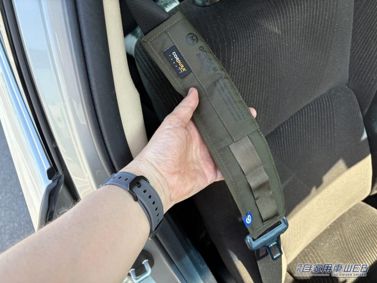 210系 トヨタクラウンのシートベルトに装着した、ゴードンミラー コーデュラシートベルトパッド（OLIVE DRABカラー）を手で持っている写真｜「シートベルトって洗えないよね…」夏場は汗でニオイも気になる。だったらコレ使ってみて！ デザイン性が高く通気性も抜群「ゴードンミラー・コーデュラ シートベルトパッド」