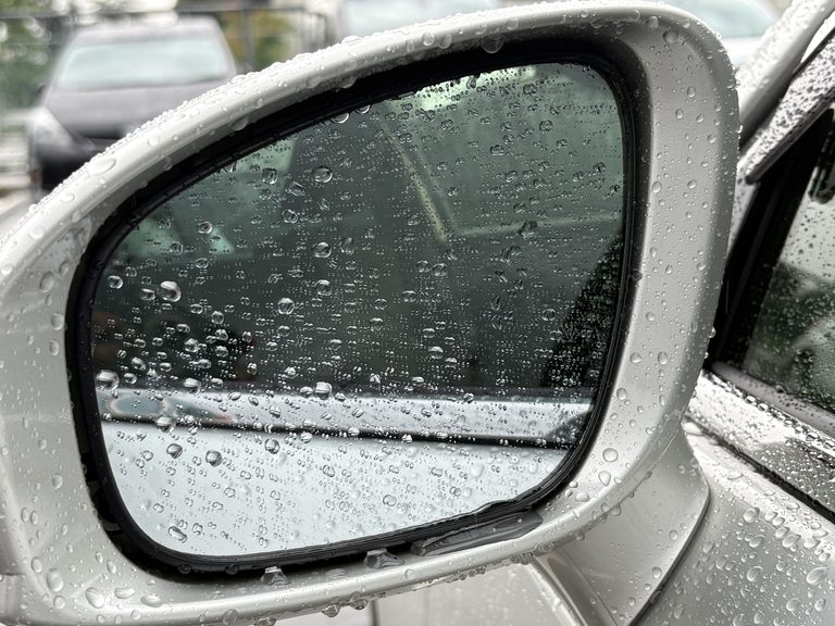 雨の日の運転で、水滴が表面に付着した210系クラウンの、助手席側のサイドミラー｜「その手があったか…」水滴で見えない助手席側ドアミラー。運転席から一気にクリアにする方法。伸縮式ワイパーを実際に購入！ 隠れた名作カーグッズだと確信した理由