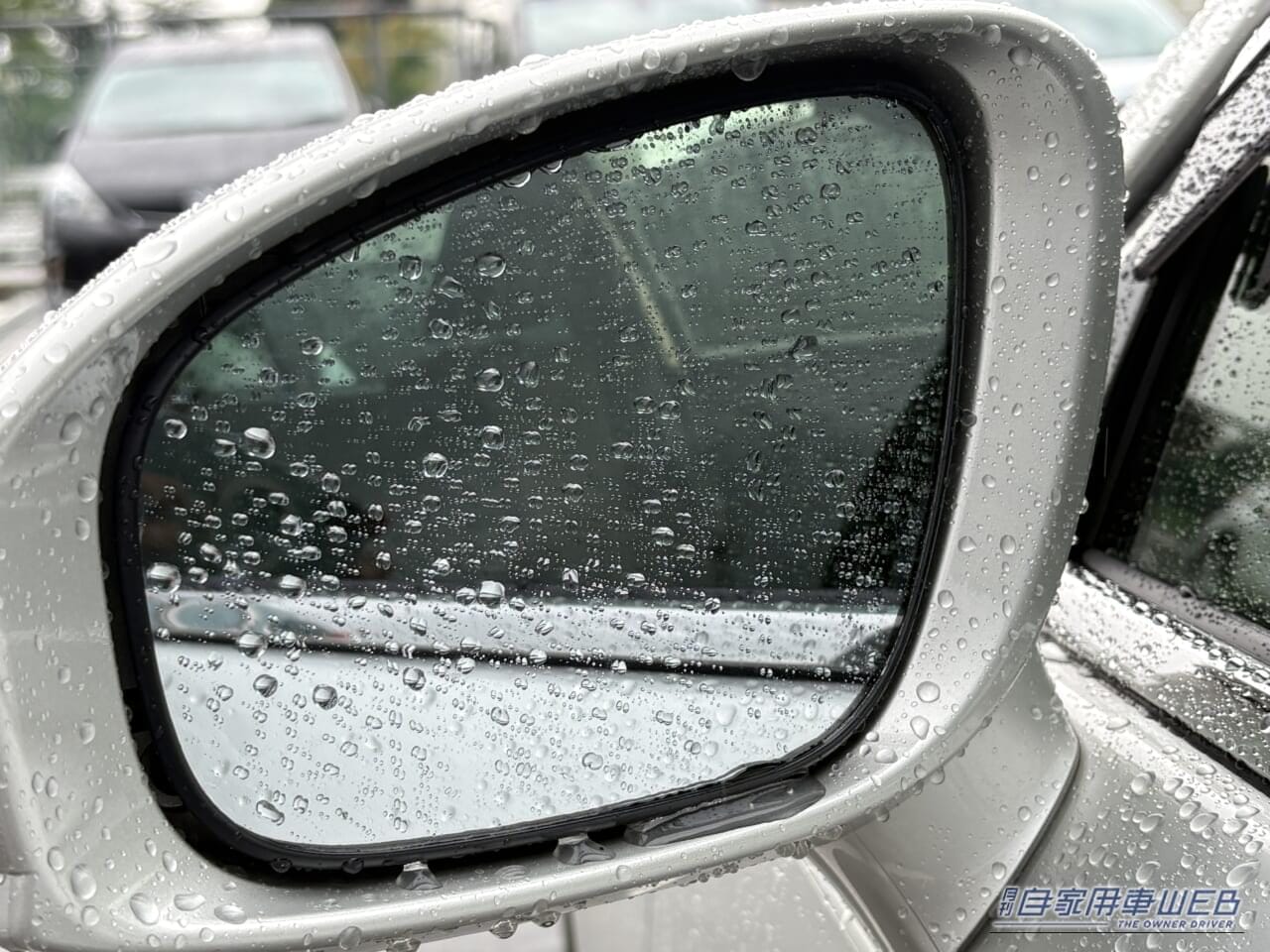 雨の日の運転で、水滴が表面に付着した210系クラウンの、助手席側のサイドミラー｜「その手があったか…」水滴で見えない助手席側ドアミラー。運転席から一気にクリアにする方法。伸縮式ワイパーを実際に購入！ 隠れた名作カーグッズだと確信した理由