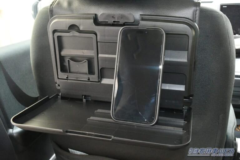 星光産業 EXEA「EB-209 リアトレイ」のスマホ用スリットを使用してスマホを立てかけている写真｜「まるで純正品のように車内に馴染む」ヘッドレストに装着するだけでOK！ 後席の快適性が向上！ 幅広い車種に対応する［EXEA EB-209 リアトレイ］を愛車に装着！