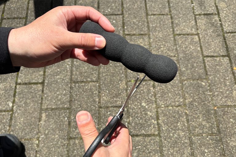 カーボーイのグリップゴム ドアレバー（黒）をカットしている写真｜「使ってみたら最高だった…」名門工具メーカーが作った意外なギア。ドアストライカーに装着するだけでOK！ 車内換気にも使える［KTC・ドアストッパー AP902A］
