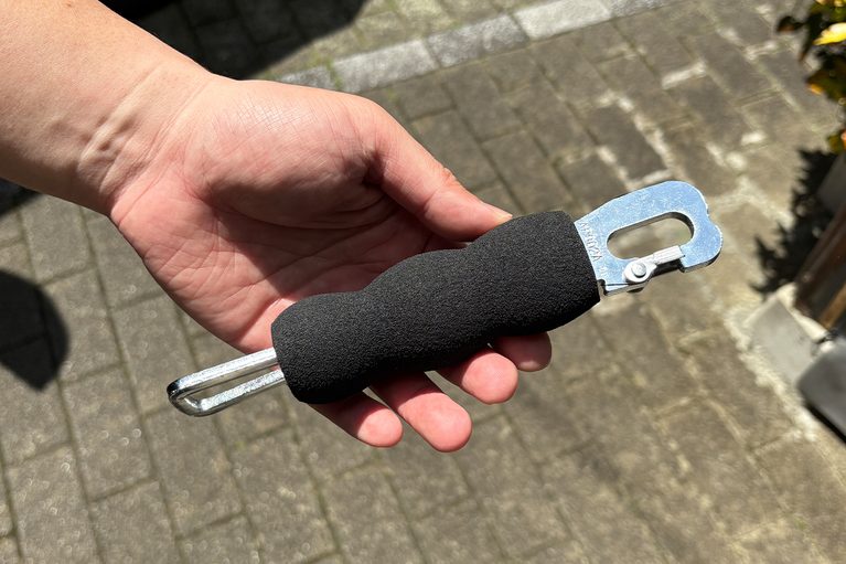 カーボーイのグリップゴム ドアレバー（黒）を、京都機械工具（KTC）のドアストッパー AP902Aに装着した状態の写真｜「使ってみたら最高だった…」名門工具メーカーが作った意外なギア。ドアストライカーに装着するだけでOK！ 車内換気にも使える［KTC・ドアストッパー AP902A］