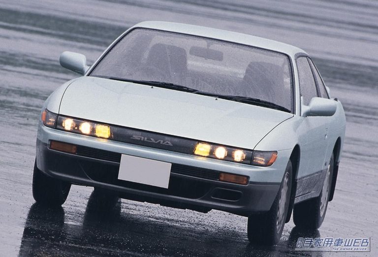雨の道路を走る、日産のS13型シルビア 1.8 Q’s｜「えっ 発売からもう38年なんだ…」見た目はナンパ・走りは本気！ 美しいデザインとプロジェクターヘッドランプが印象的な［日産・S13型シルビア］