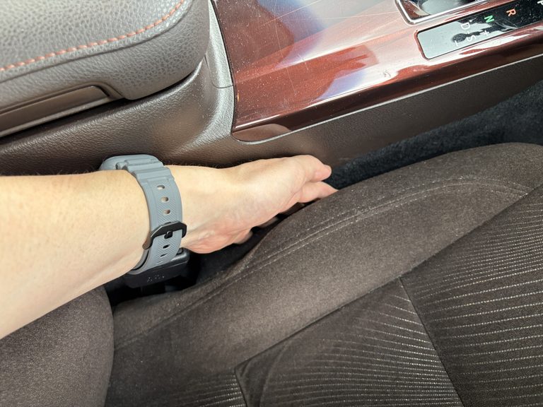 210系クラウンの運転席とセンターコンソールの隙間に手をいれている写真｜「めっちゃイライラする…」物を落としやすいシートの隙間。このデッドスペースにぴったりハマる小物入れを購入！ 簡単設置のカーグッズを紹介！